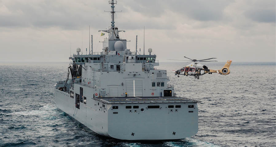 A large boat is traveling on the water, with a helicopter flying above it. The helicopter is carrying a person, possibly a passenger or a crew member. The scene captures the interaction between the boat and the helicopter, showcasing the maritime transportation and the use of helicopters for travel or rescue purposes. AI generated content