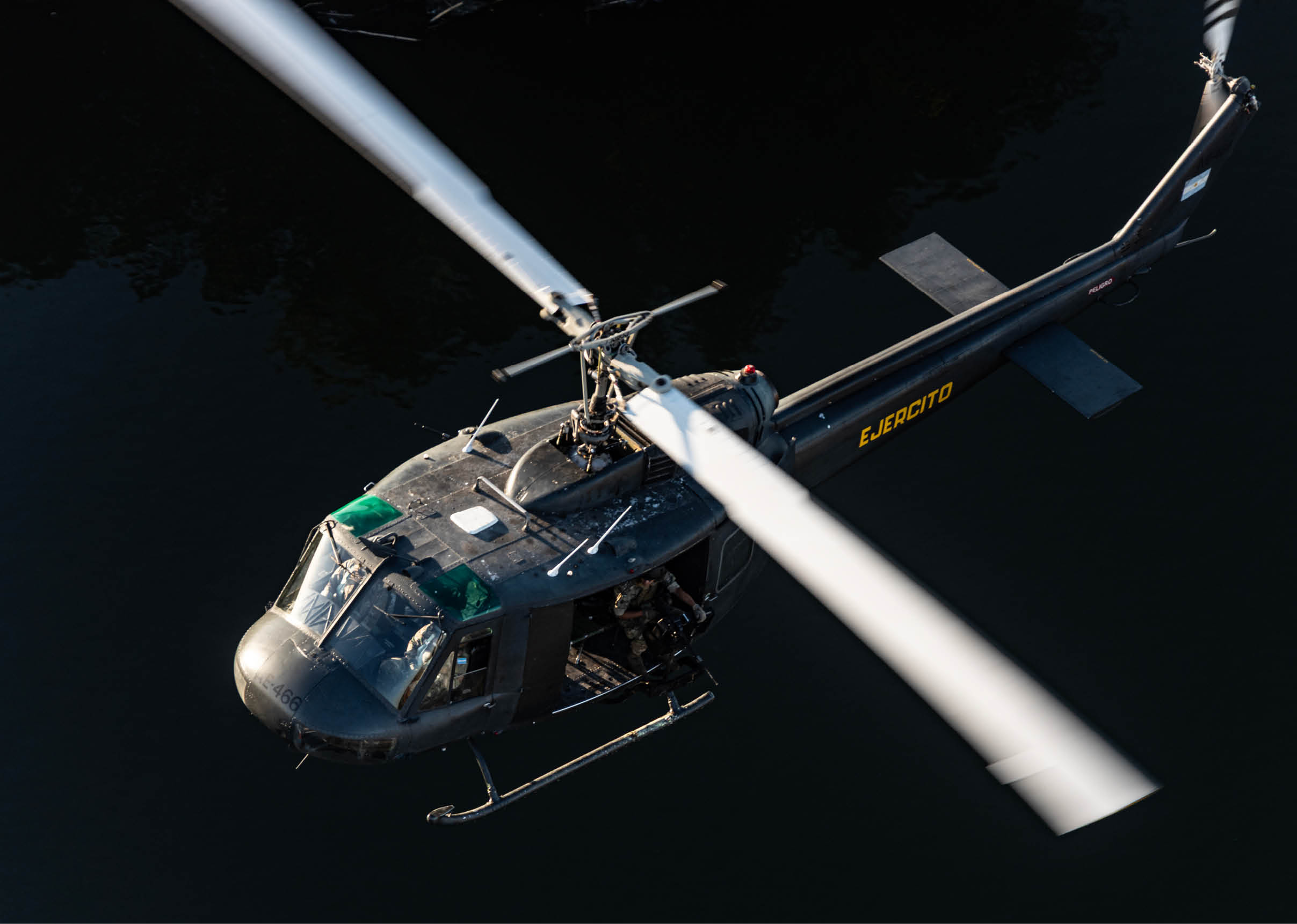 A helicopter with a large propeller is flying over a body of water. Description generated by AI