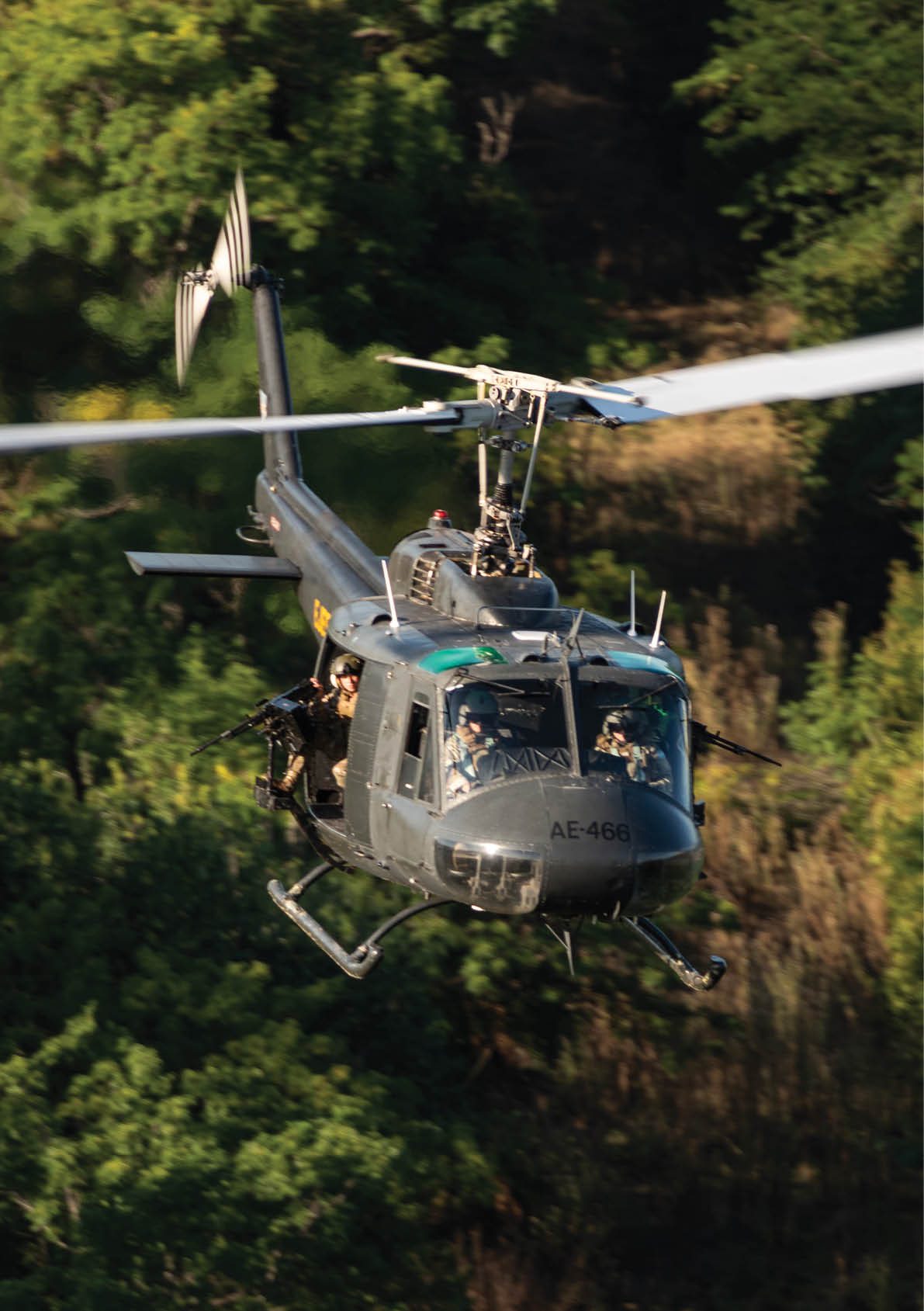 A helicopter flying over a forest. Description generated by AI