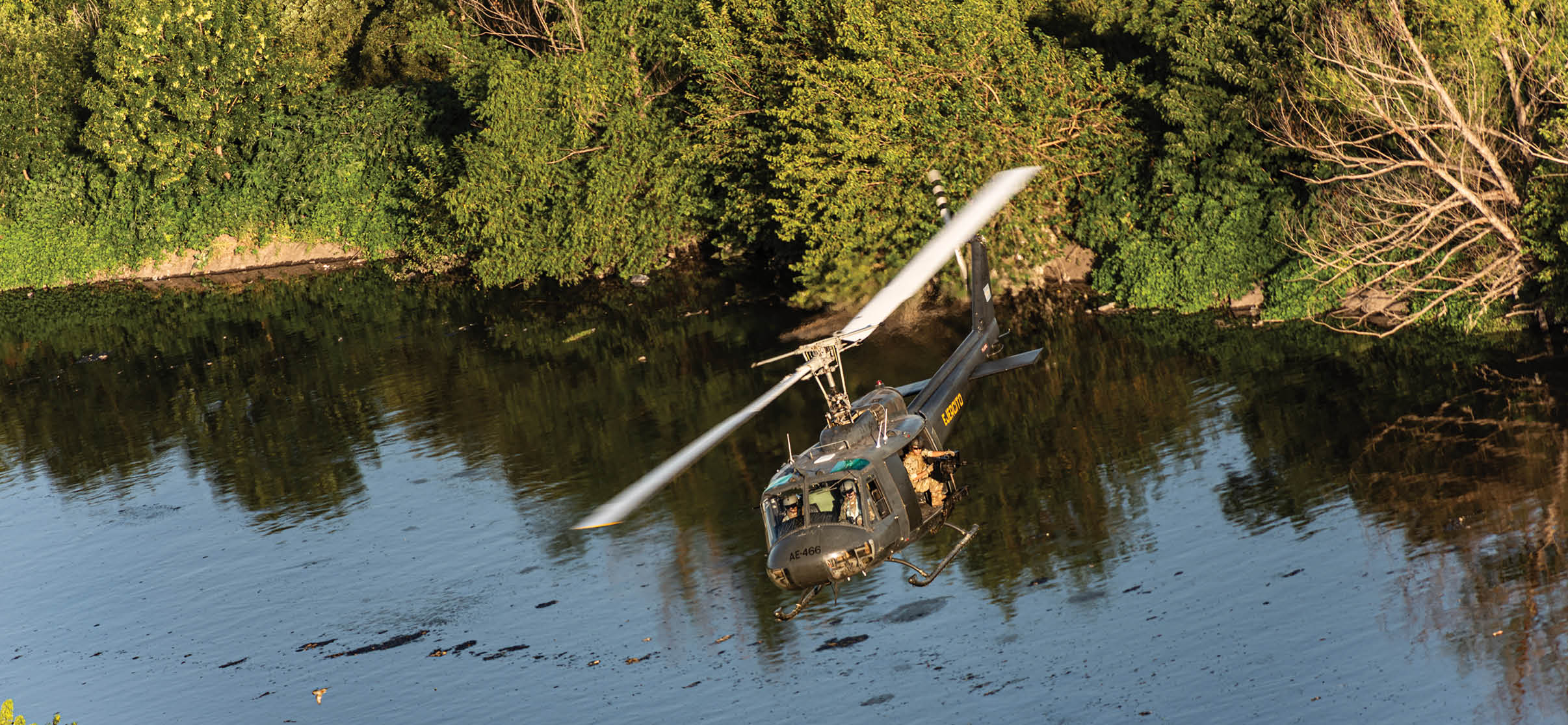 A helicopter flying over a body of water. Description generated by AI