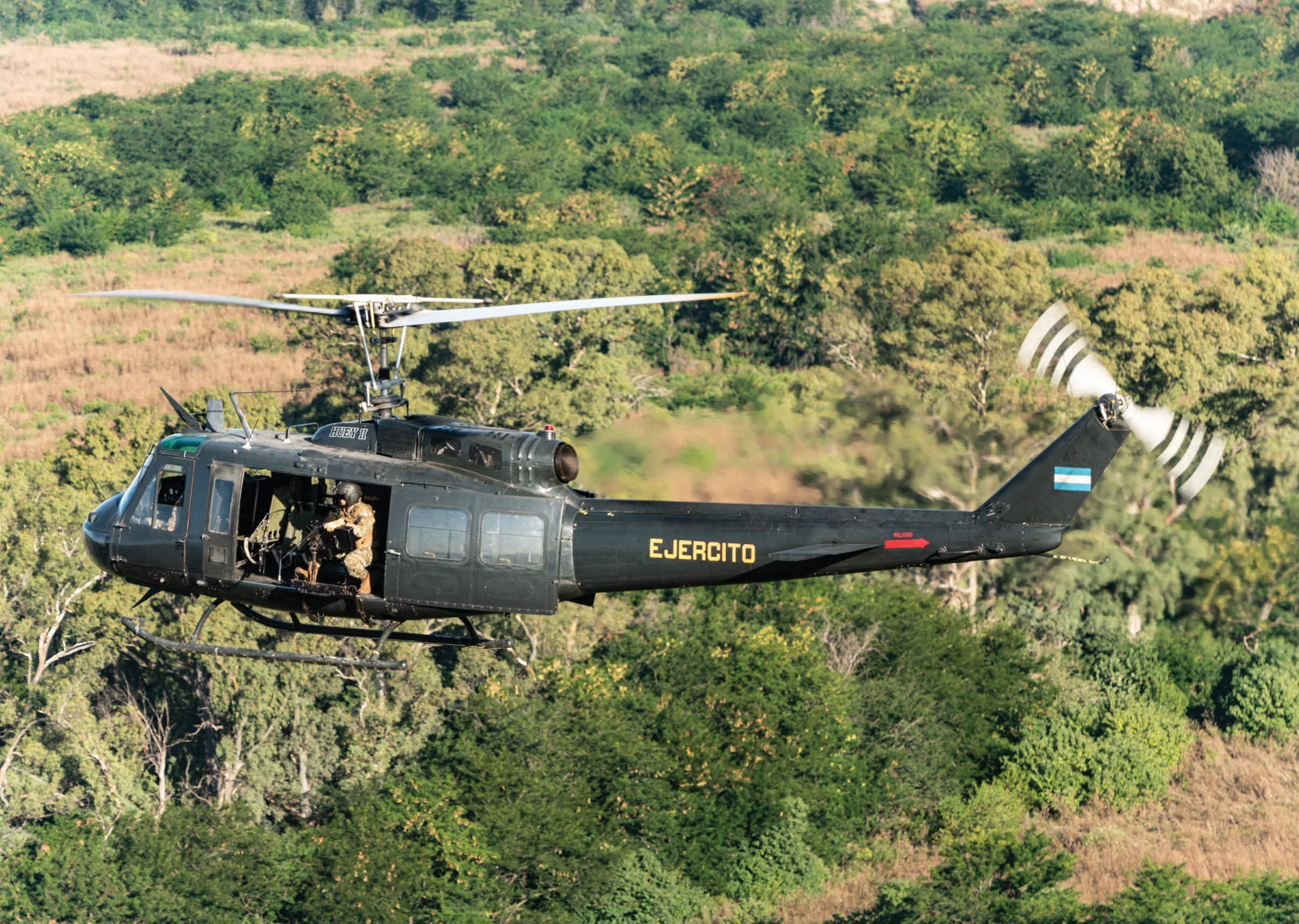A helicopter with the word “Eureka" on the side is flying over a forest. Description generated by AI