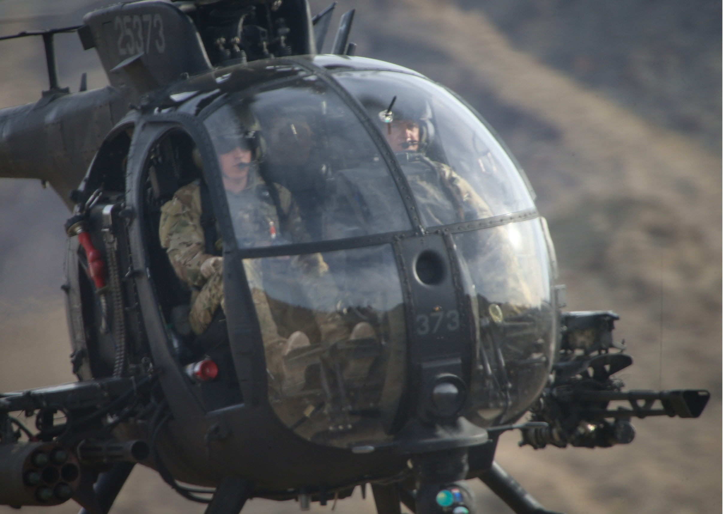 Two men in military uniforms are in a helicopter. Description generated by AI