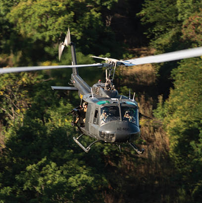 A helicopter flying over a forest. Description generated by AI
