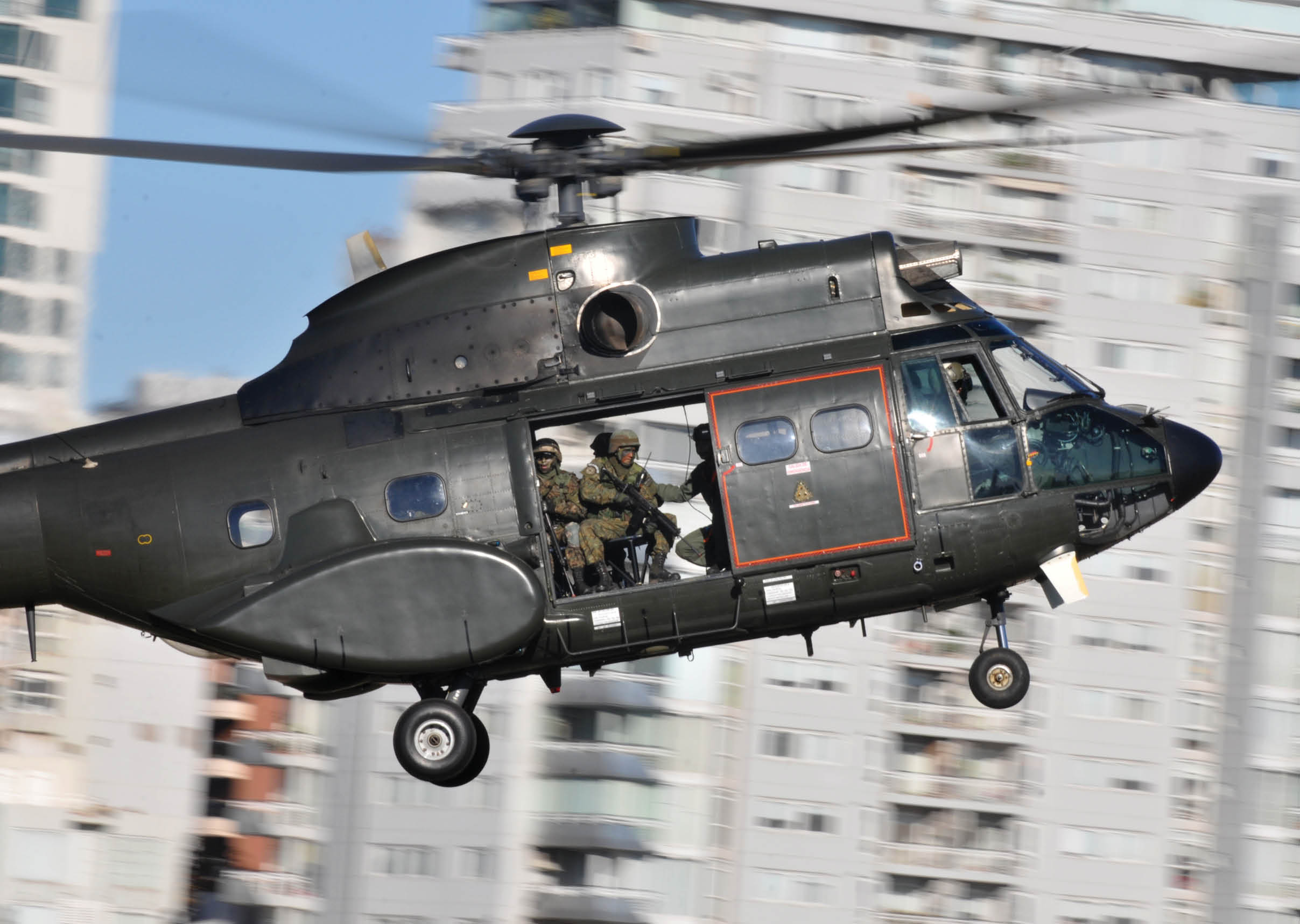 A helicopter flying in the air with a man in a uniform on it. Description generated by AI