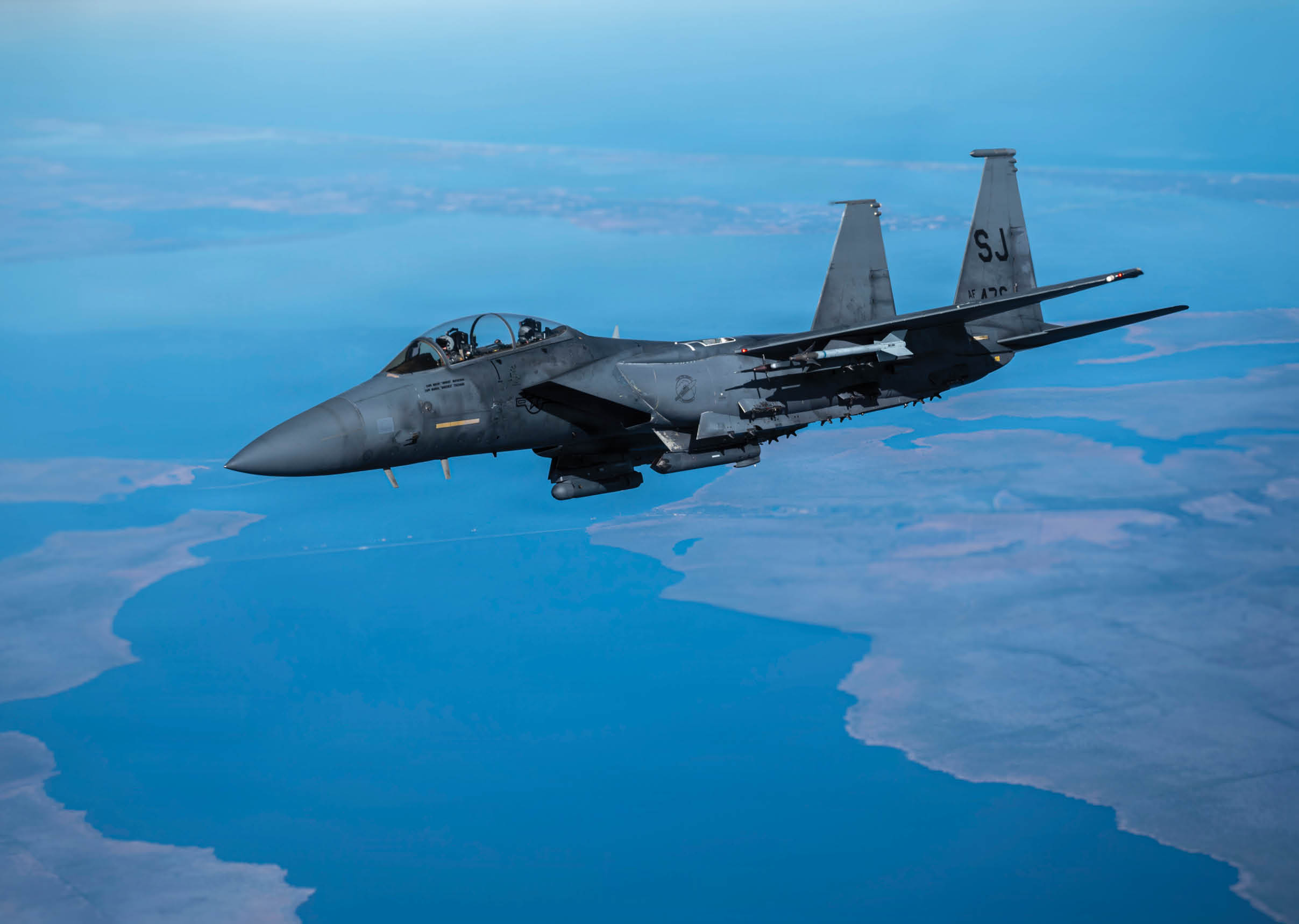 A fighter jet flying over a body of water. Description generated by AI