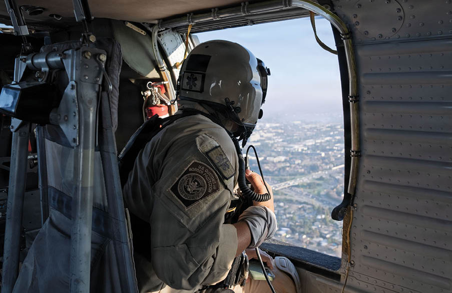 A man in a helicopter looking out the window. Description generated by AI