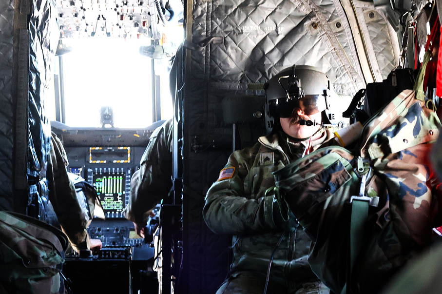 A man wearing a helmet is sitting in a military plane. Description generated by AI