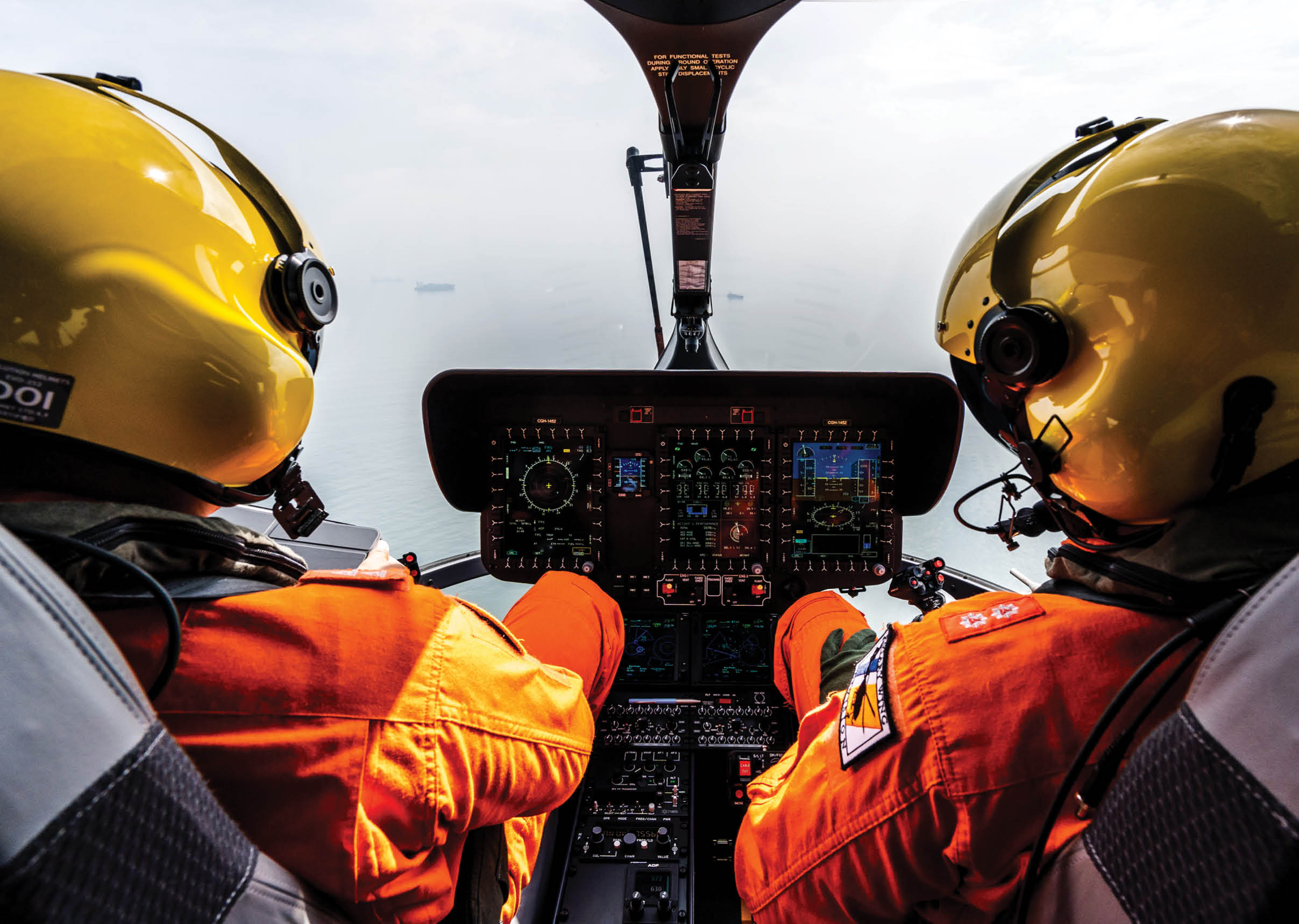 Two people in orange and yellow helmets are in a helicopter. Description generated by AI