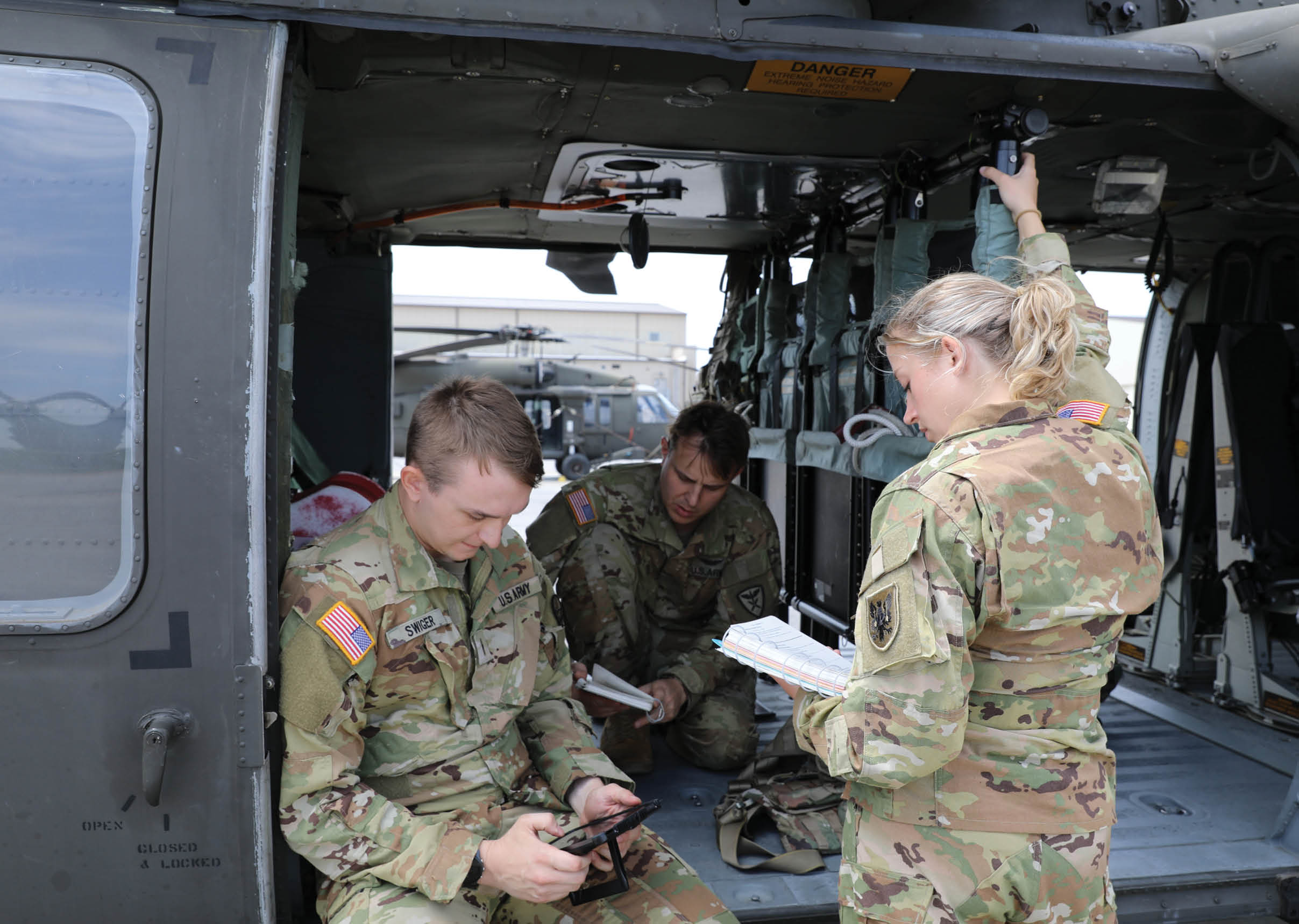 A group of people in military uniforms are inside a helicopter. Description generated by AI