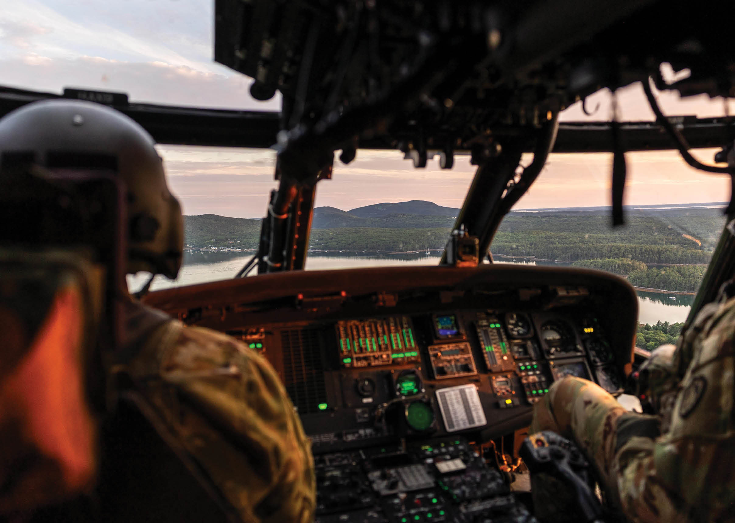 Two men in military uniforms are in a helicopter. Description generated by AI