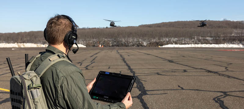 A man wearing a headset and holding a tablet. Description generated by AI
