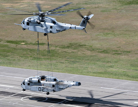 A helicopter is lifting a military vehicle off the ground. Description generated by AI