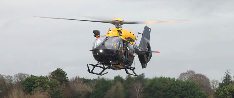 A helicopter with a yellow top is flying in the air. Description generated by AI