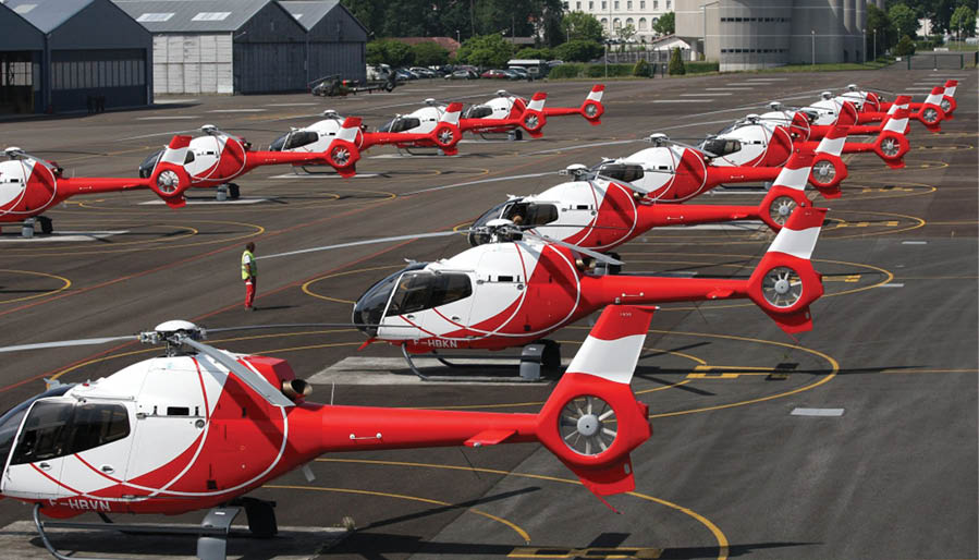 A row of red and white helicopters parked on a runway. Description generated by AI