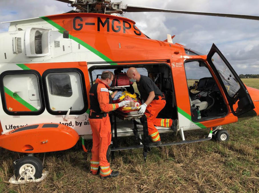 A man in an orange and black suit is being lifted out of a helicopter. Description generated by AI
