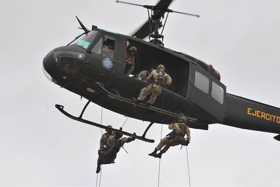 A group of soldiers are hanging from a helicopter. Description generated by AI