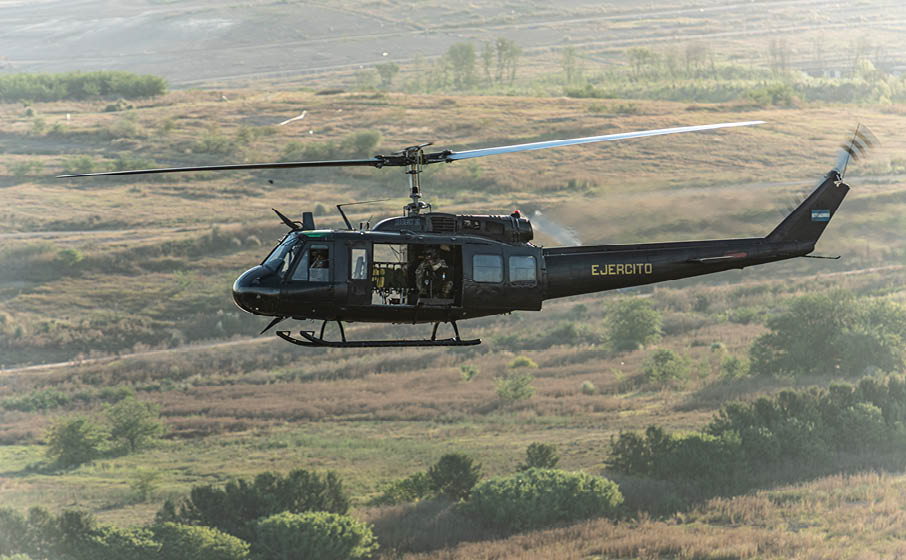 A helicopter flying over a field. Description generated by AI