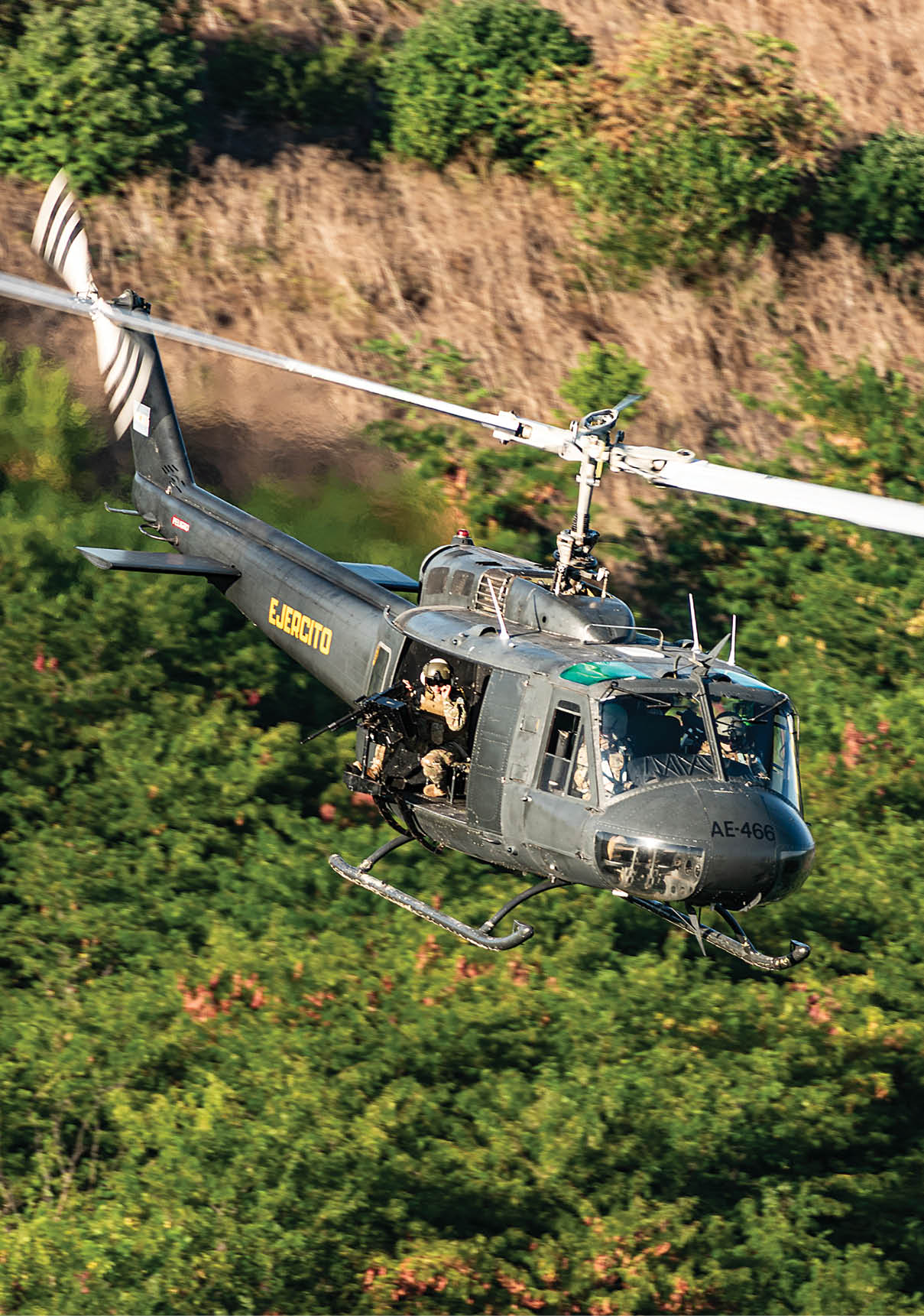 A helicopter is flying over a field of trees. Description generated by AI