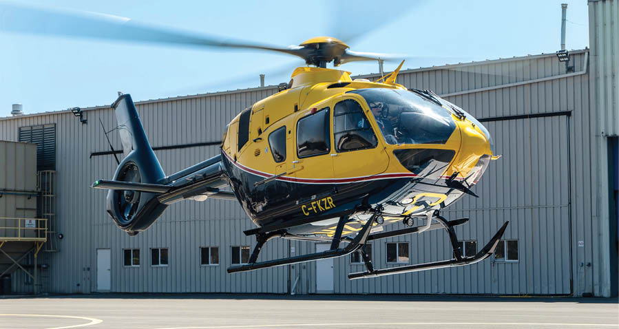 A yellow and black helicopter is flying in the air. Description generated by AI