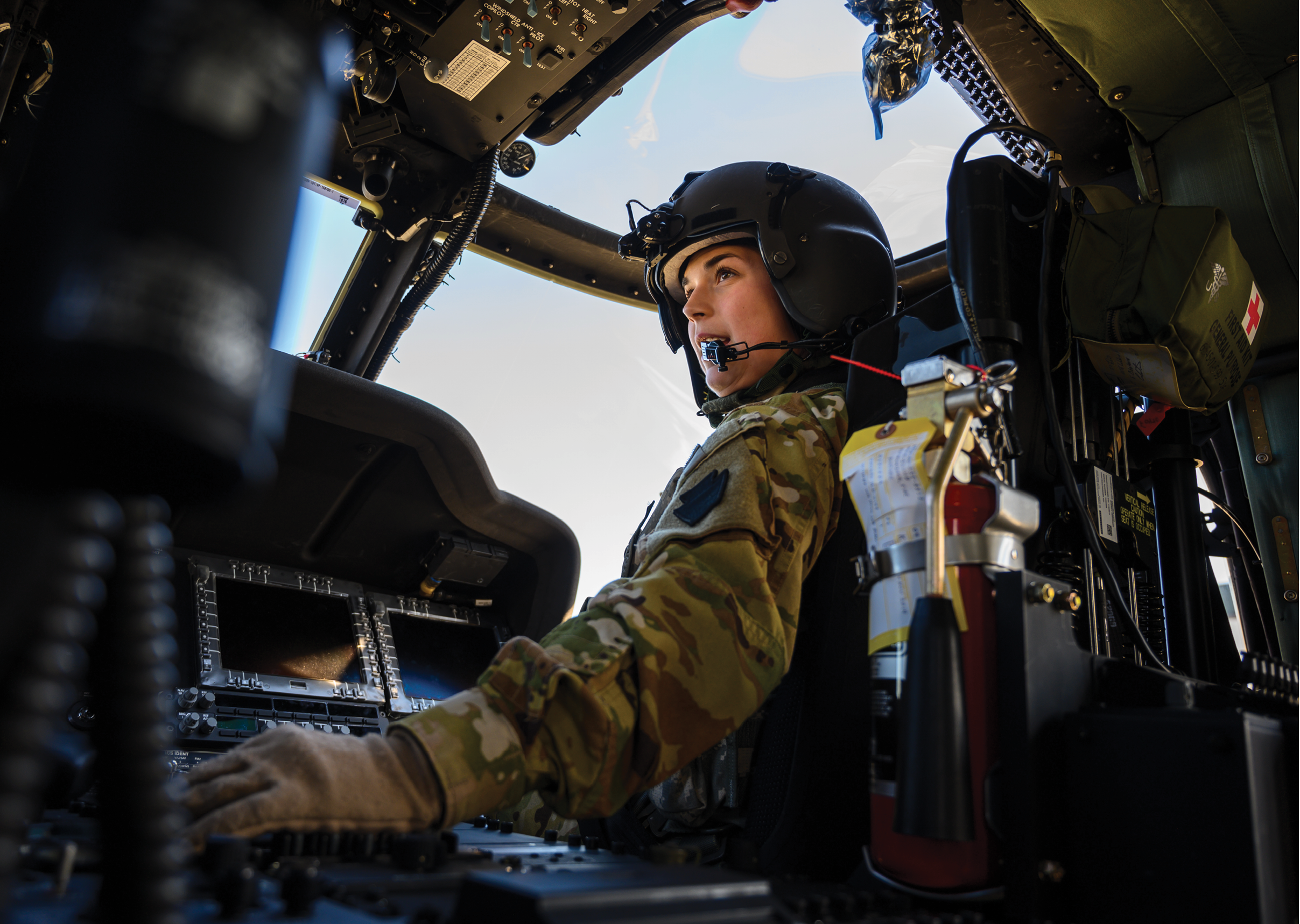 A woman wearing a helmet and a uniform is sitting in a cockpit of a plane. Description generated by AI