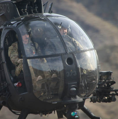 Two men in military uniforms are in a helicopter. Description generated by AI