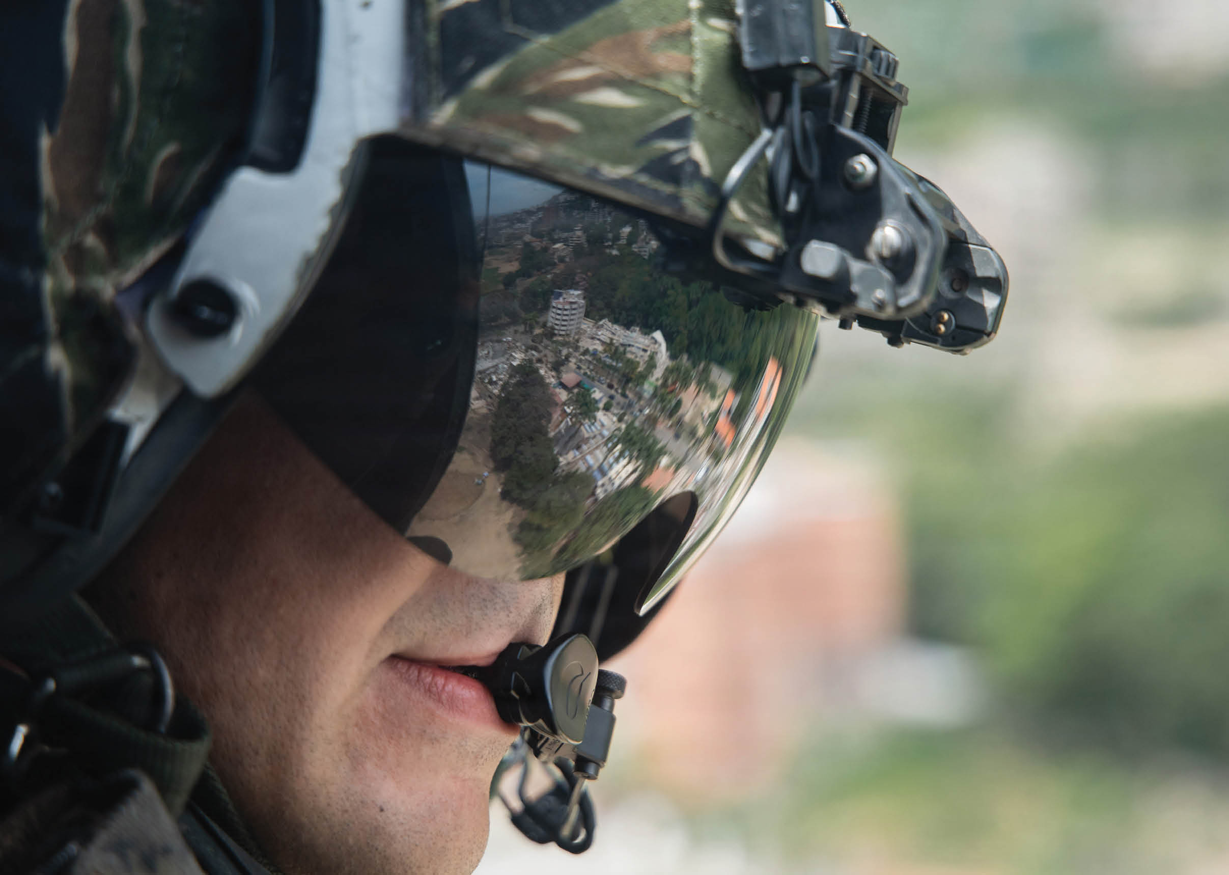 Two men in military uniforms are in a helicopter. Description generated by AI
