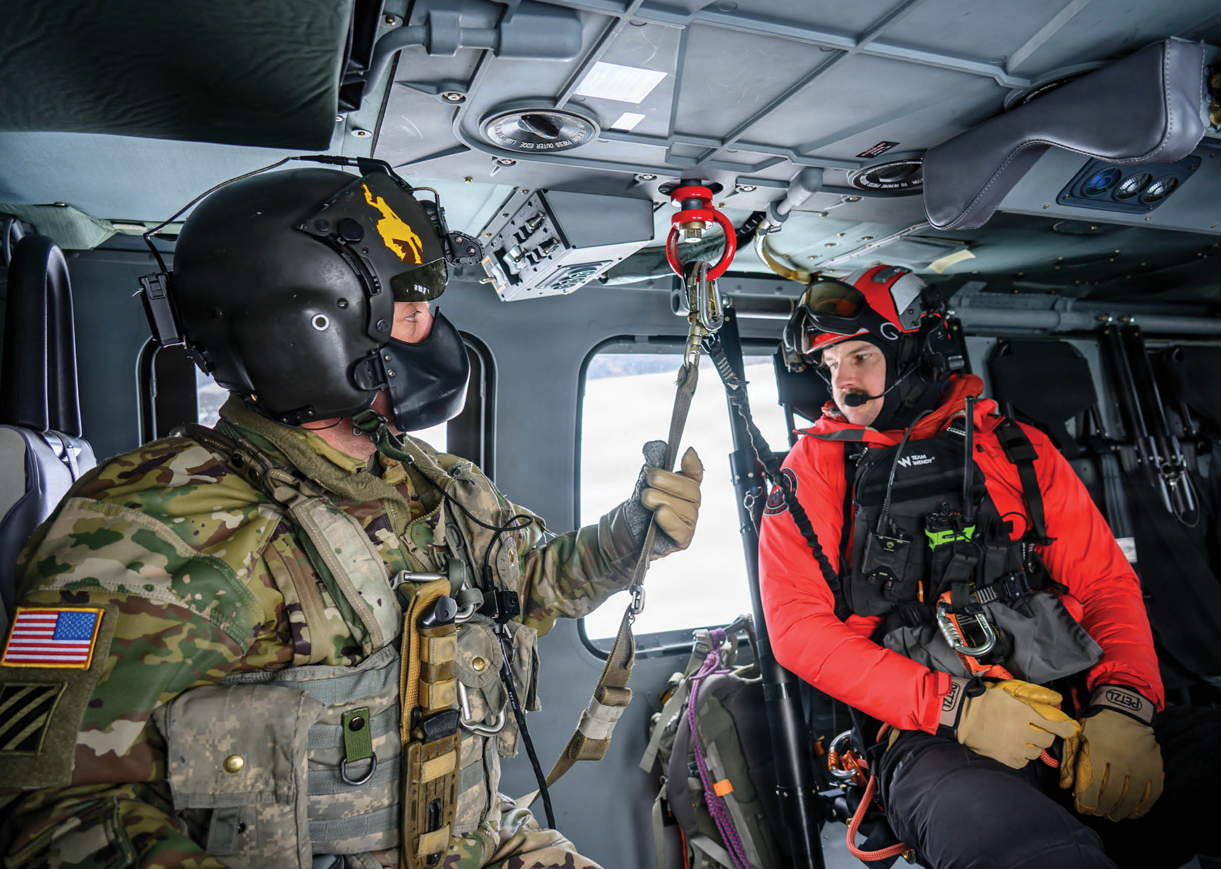 Two people in orange and yellow helmets are in a helicopter. Description generated by AI