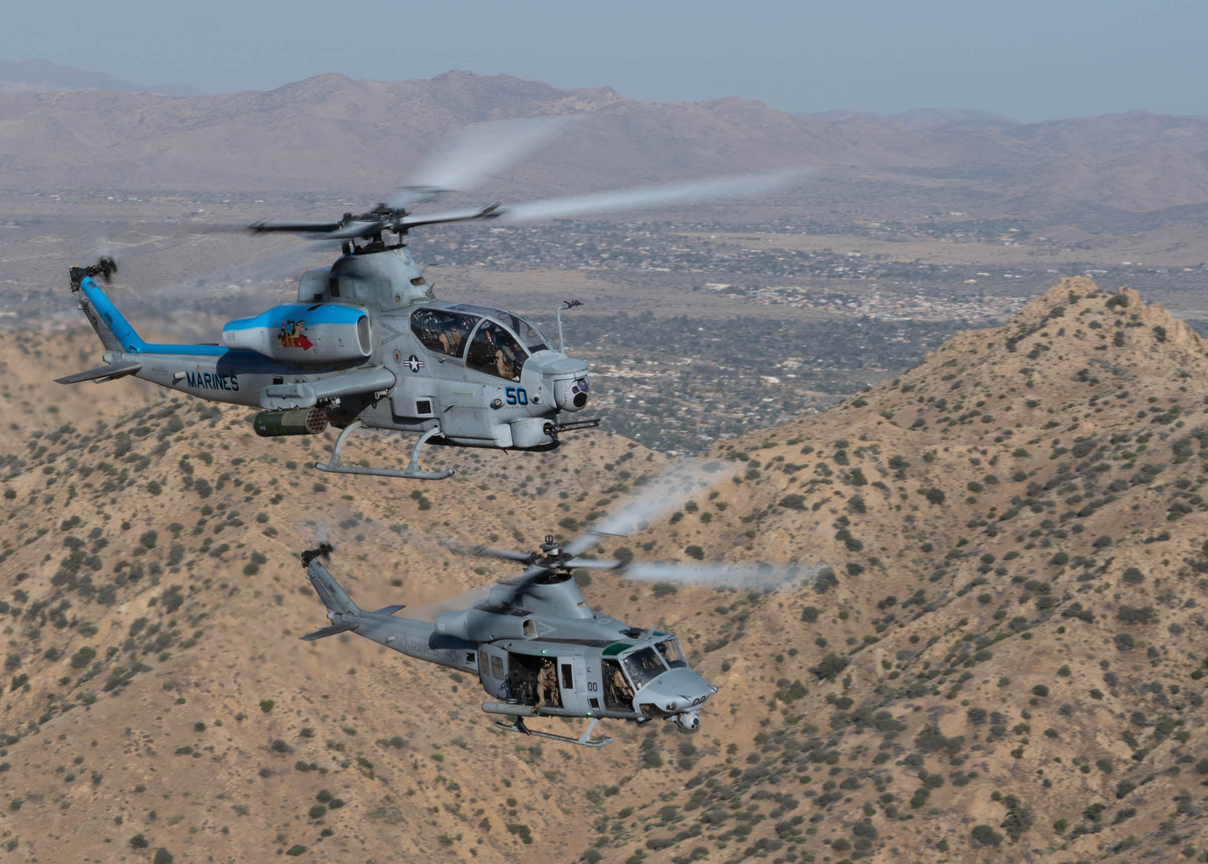 A man in a camouflage uniform is watching a helicopter fly by. Description generated by AI