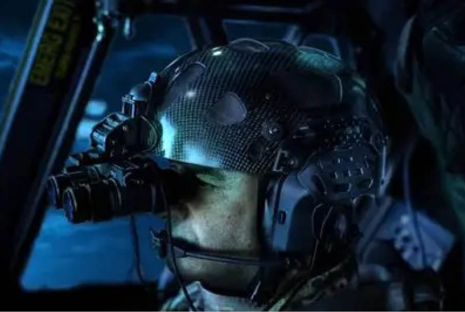 A person wearing a tactical helmet with night vision goggles is seated inside a dimly lit vehicle or aircraft. Description generated by AI