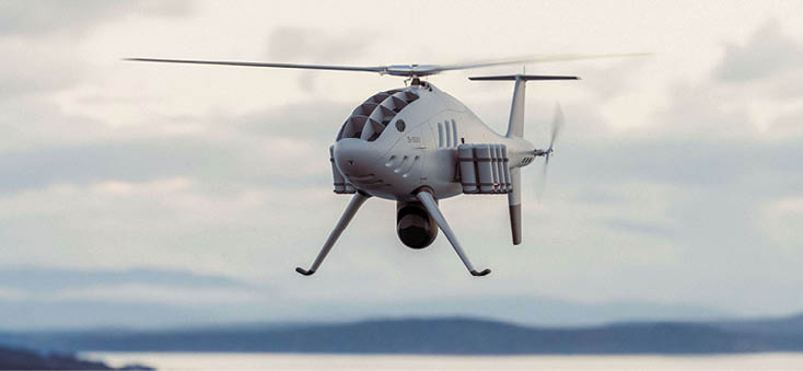 A group of people standing in front of a table with an American flag and a helicopter in the background. Description generated by AI