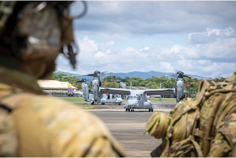 A man in a military uniform is watching two military helicopters on a runway. AI generated content