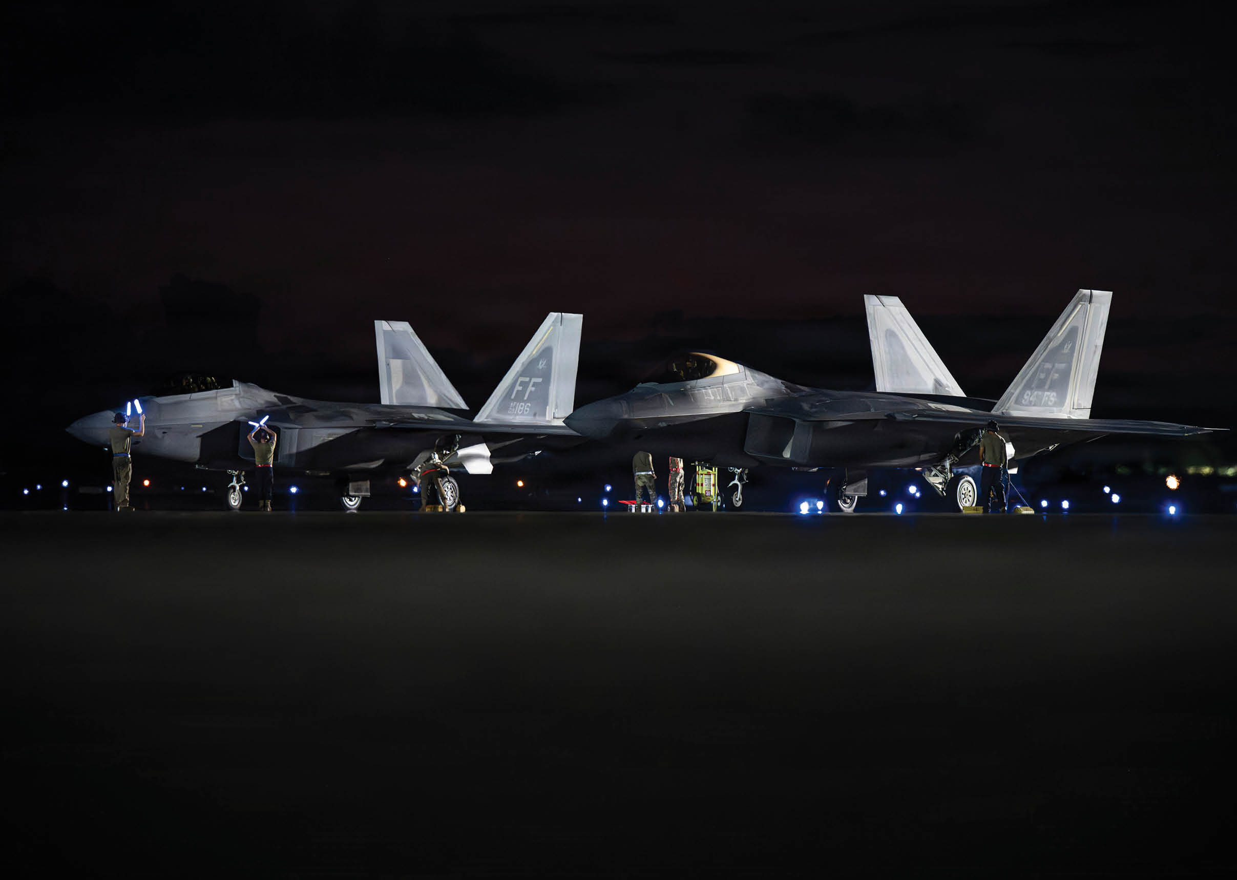 Two fighter jets are parked on the runway at night. AI generated content