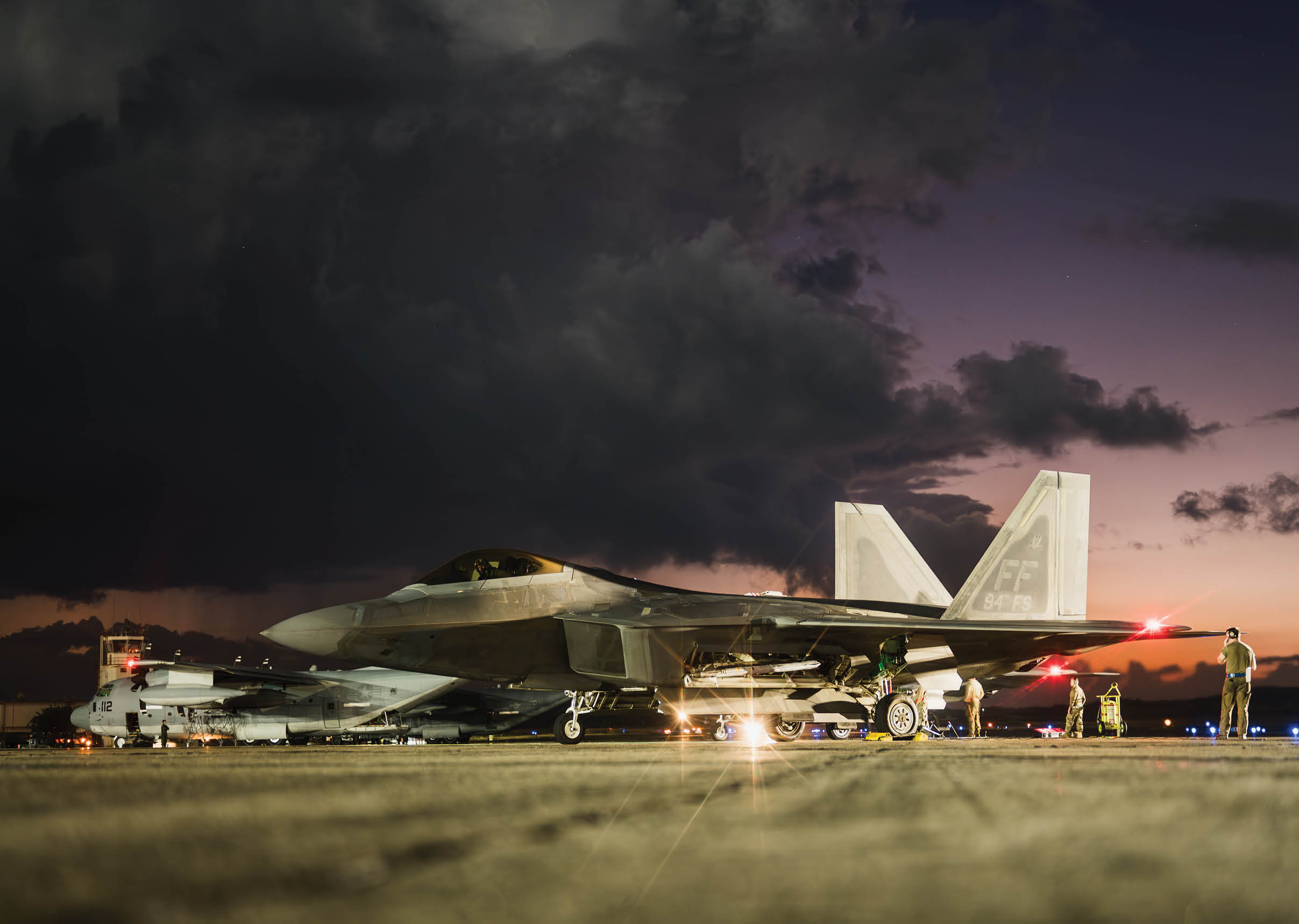 Two fighter jets are parked on a runway at night. AI generated content