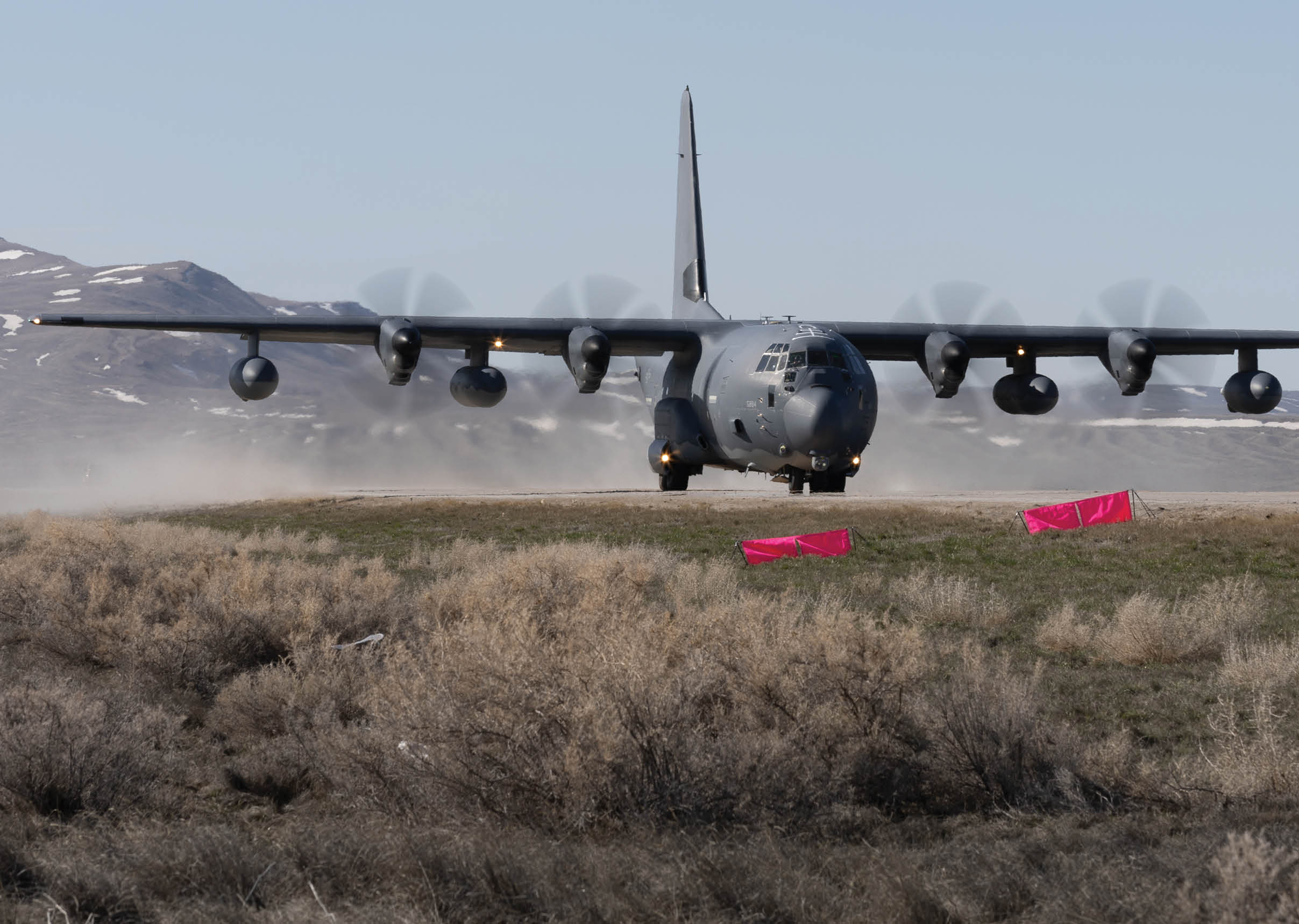 A large military plane is flying low over a field with a red object on the ground. AI generated content