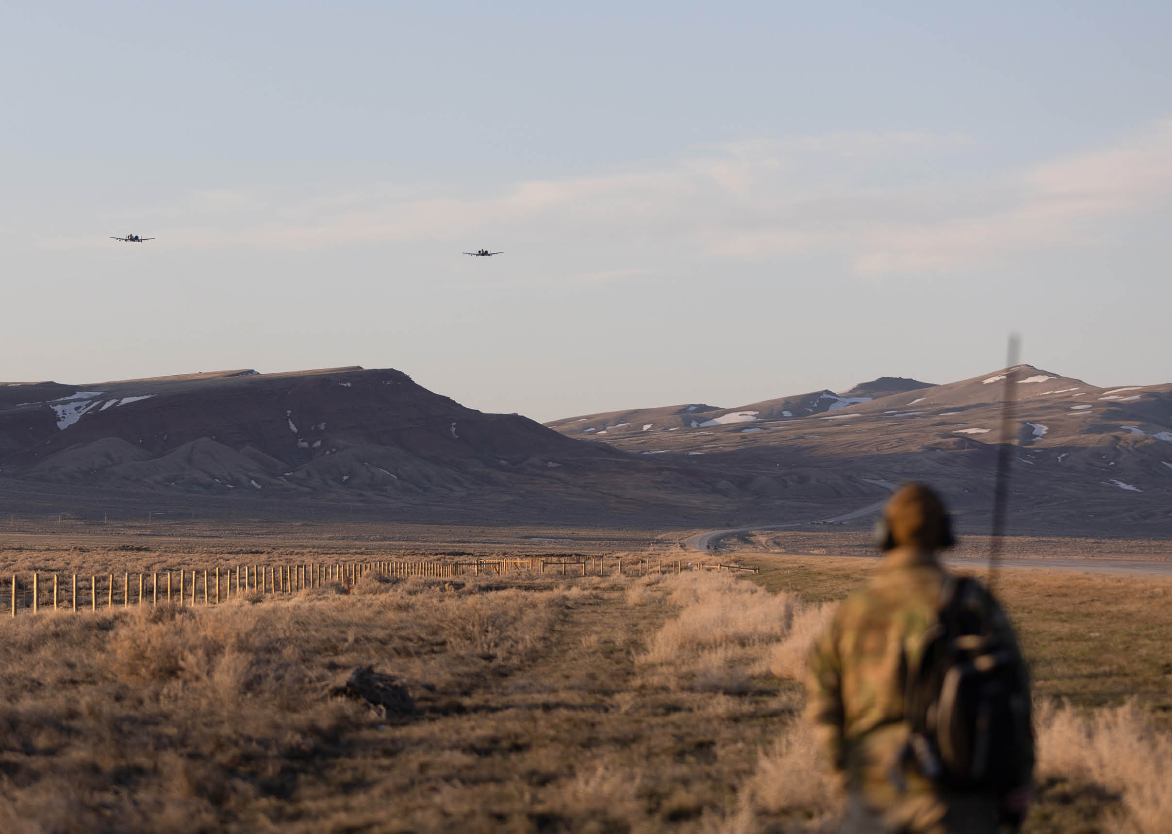 Two airplanes flying in the sky over a man walking in a field. AI generated content