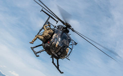 A man is hanging from a helicopter, wearing a camouflage uniform. AI generated content