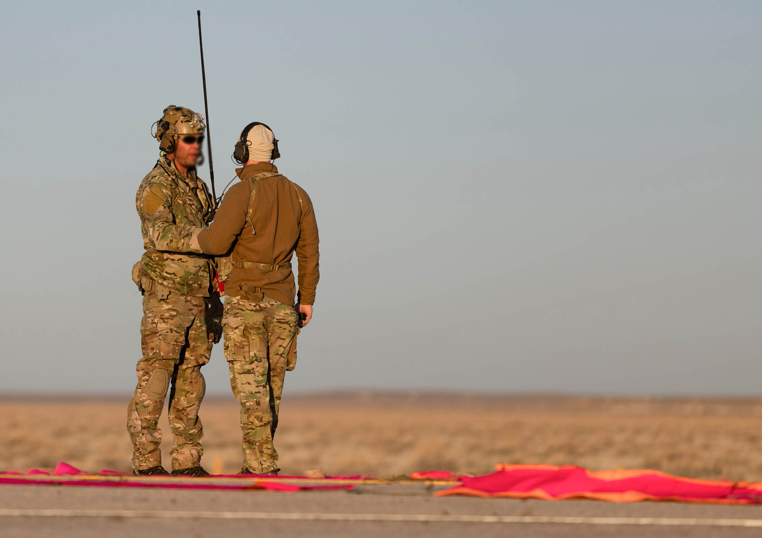 Two men in camouflage uniforms are standing on a red tarp. AI generated content