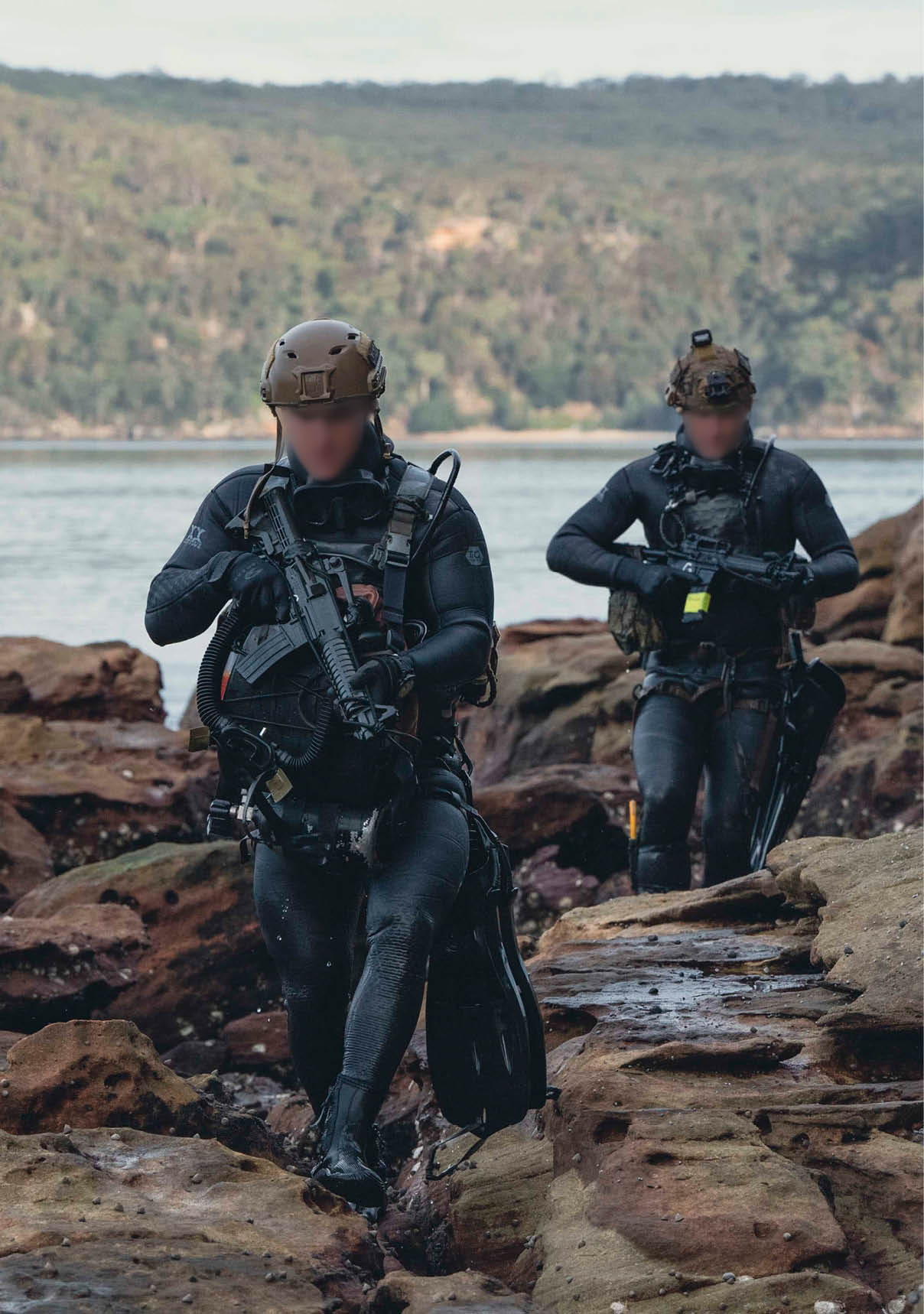 Two men in wet suits are walking on rocks near the water. AI generated content