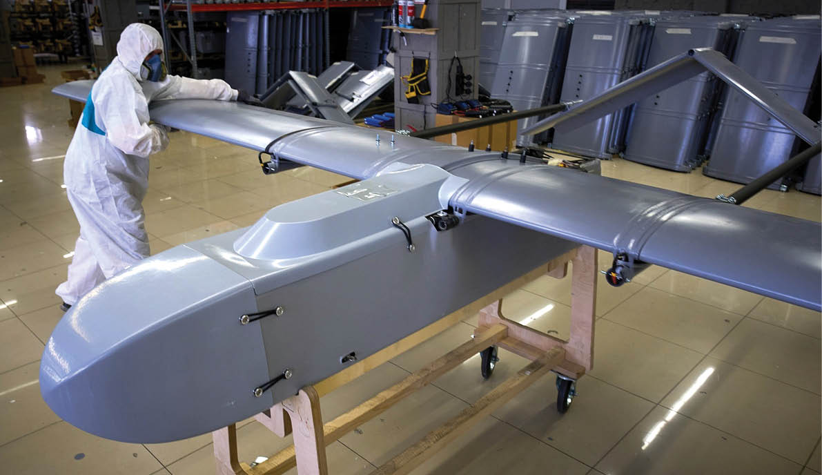 A man wearing a white suit is working on a drone in a factory. AI generated content