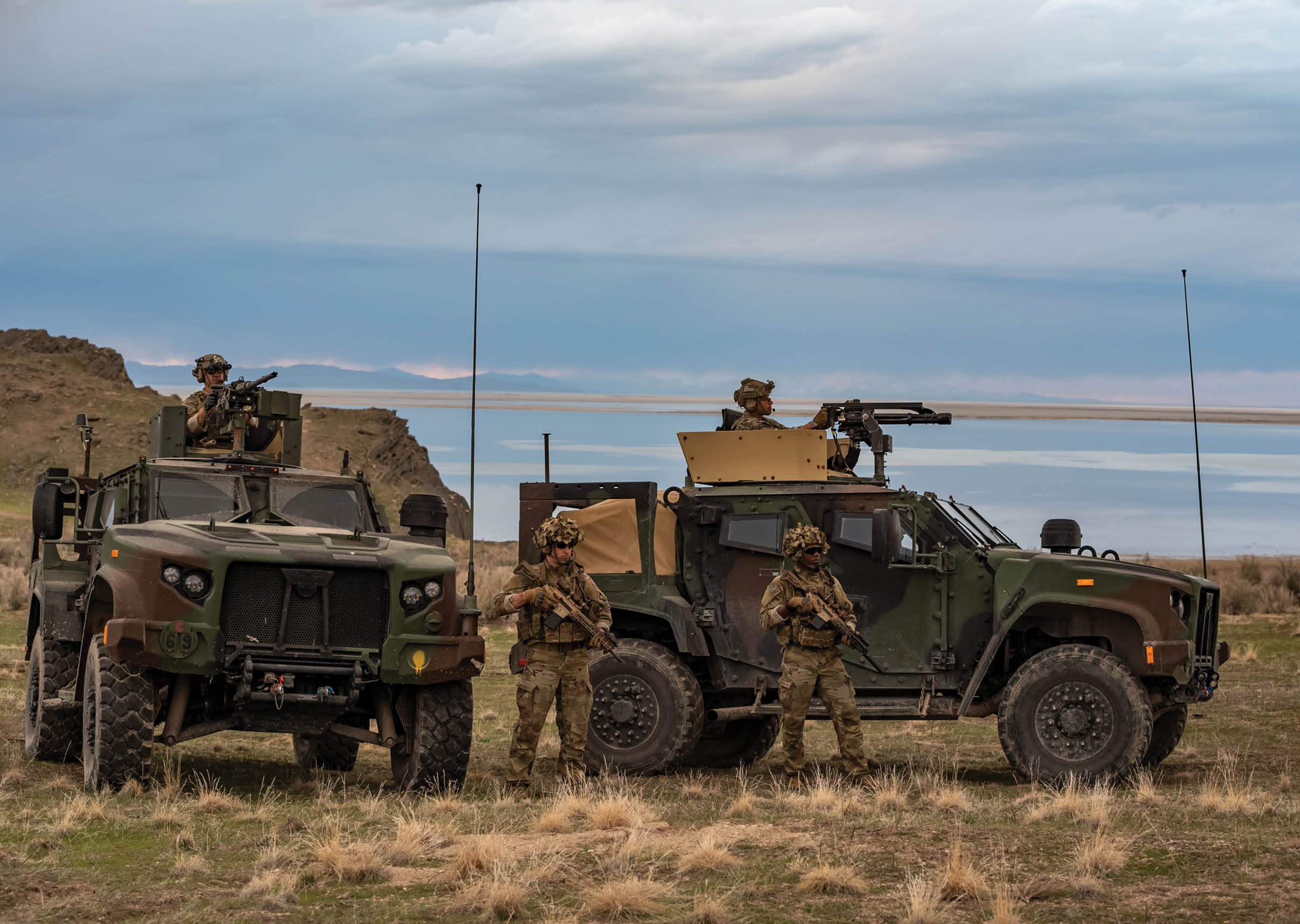 Three military personnel are standing next to their vehicles, which are parked in a field. AI generated content