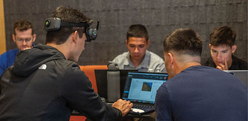 A group of men wearing headphones and glasses are sitting in front of computers. AI generated content