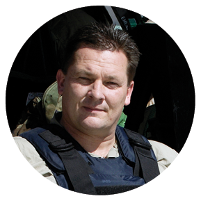 A man wearing a bulletproof vest and holding a gun stands next to a helicopter. AI generated content