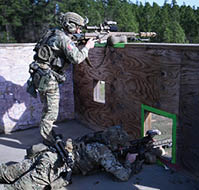 Two men in camouflage are playing a video game. Description generated by AI