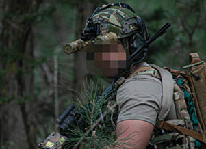 A man wearing a camouflage helmet and carrying a backpack. Description generated by AI