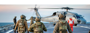 A group of soldiers walking on a boat with their bags. Description generated by AI