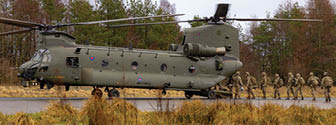 A group of soldiers are walking in front of a large army helicopter. Description generated by AI