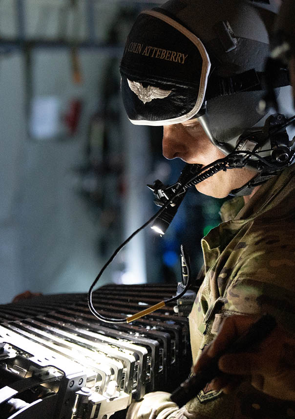 A man wearing a helmet and a military uniform is looking at a piece of equipment. Description generated by AI