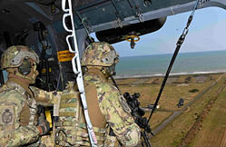 Two soldiers in camouflage uniforms are on a helicopter. Description generated by AI
