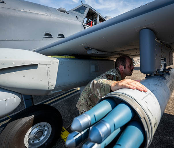 A man is touching the side of a missile. Description generated by AI