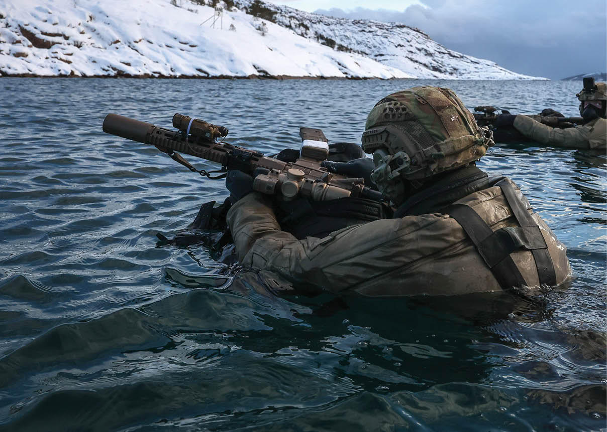 A man in a camouflage uniform holding a gun. Description generated by AI